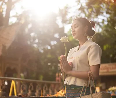 a beautiful asian woman in a traditional thai lanna dress is making a wish in a temple