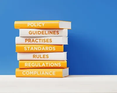 books of compliance and regulations in front grey wall