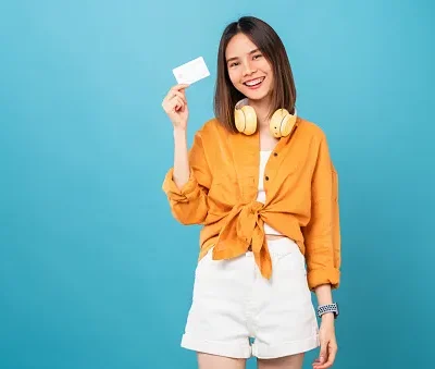 cheerful beautiful asian woman holding mockup credit card on blue background