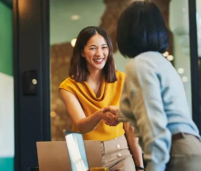 cheerful businesswomen shaking hands in meeting room