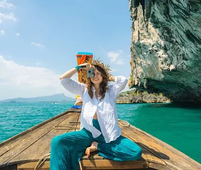 cheerful woman traveling with thai taxi boat and photographing with point and shoot camera