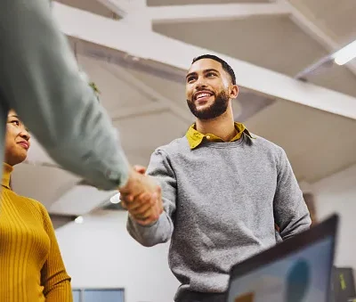 low angle view of cheerful executive shaking hands with colleague in office