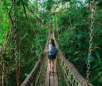 woman walking on rope bridge in lush jungles a