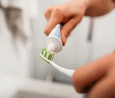 young man putting on toothpaste to brush his teeth in the bathroom